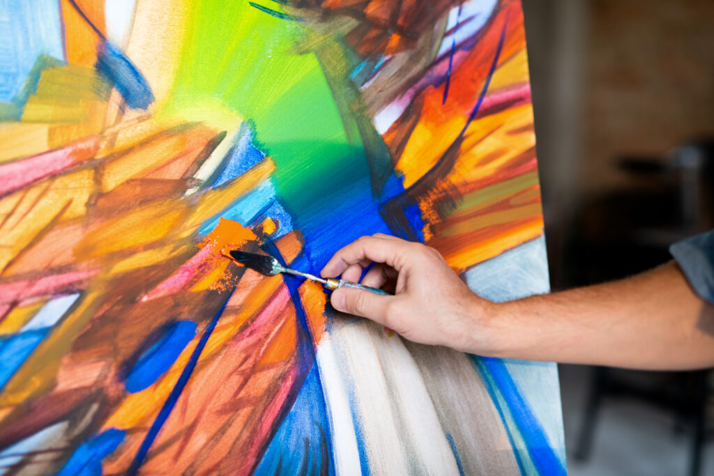 Hand of contemporary painter with special instrument mixing colors on paper